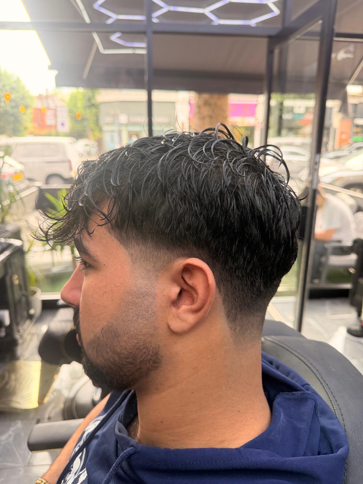 Curly textured top with sharp low fade and beard blend